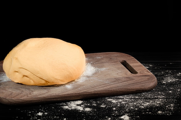 Préparation de la pâte. Pâte à levure pour tartes. Rouleau à pâtisserie avec de la farine sur une sombre