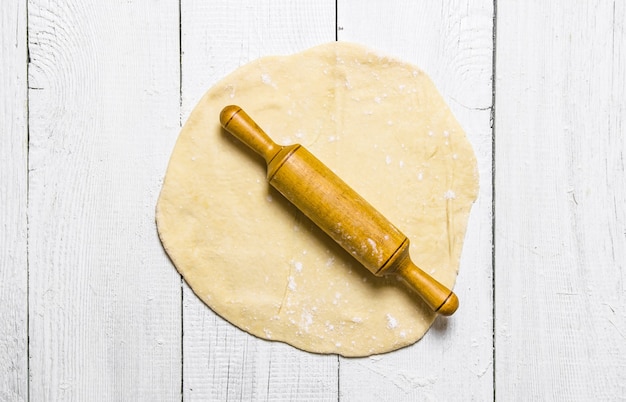 Préparation de la pâte. Prêt à rouler la pâte avec un rouleau à pâtisserie. Sur un fond en bois blanc. Vue de dessus