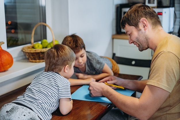 Préparation pour la célébration d'halloween. Homme de race blanche avec son mignon fils de 6 ans dessinant les yeux sur une citrouille pour faire une lanterne Jack traditionnelle. Image avec mise au point sélective. photo de haute qualité