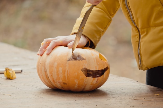 Préparation pour Halloween : citrouille de coupe fille. Fermer. Concept de décoration de vacances. Une femme prépare une citrouille-lanterne. Fête de la décoration. Petite aide.