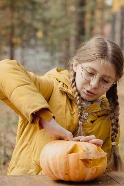 Préparation pour Halloween : la fille extrait des graines de citrouille. Fermer. Concept de décoration de vacances. Une femme prépare une citrouille-lanterne. Fête de la décoration. Petite aide.