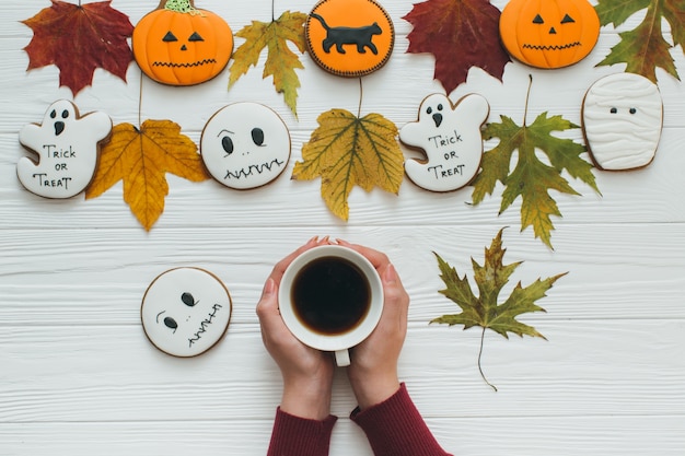 Photo une préparation pour halloween. une fille tenant une tasse de café et pain d'épice.