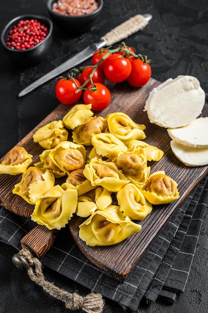 Préparation de raviolis crus à la Mozzarella et à la Tomate. Fond noir. Vue de dessus.