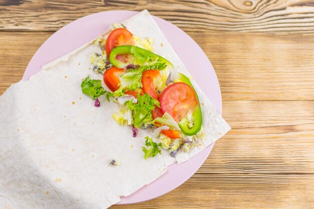 Préparation d'un rouleau de pain pita et de légumes frais sur un fond en bois Le concept d'une alimentation saine