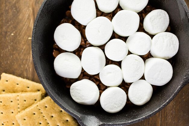 Préparation des smores dip préparé avec de grosses guimauves dans une poêle en fonte.