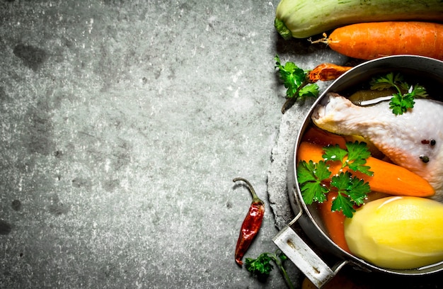 Préparation de soupe de poulet parfumée aux légumes frais. Sur la table en pierre.