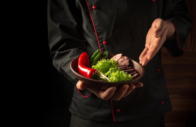 Préparation de steak de boeuf et de légumes frais Assiette avec de la nourriture dans la main du chef