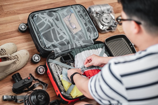 Préparation de la valise pour les vacances d'été Jeune homme vérifiant les accessoires et les choses dans les bagages Concept de vacances et de vacances