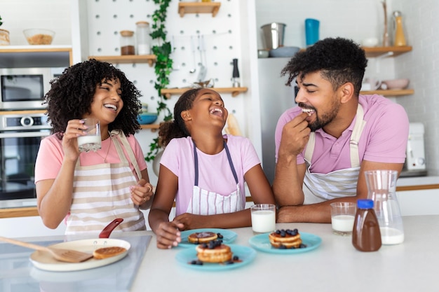 Préparer la boulangerie à la maison Aimer les conjoints de la famille afro-américaine amicale avec sa fille cuisiner des aliments ensemble à la table de la cuisine faire des crêpes maison