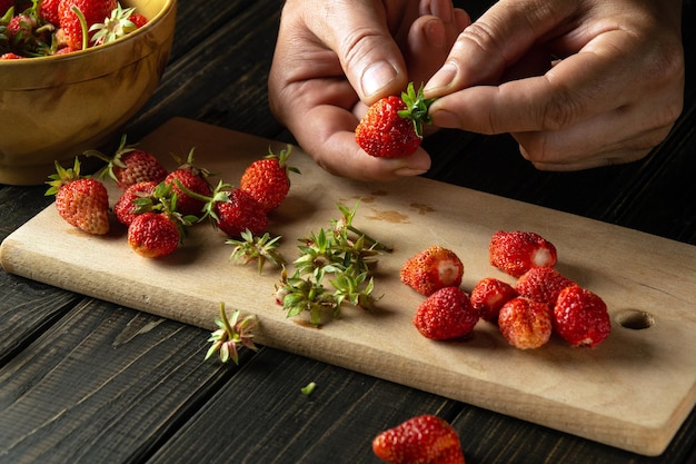 Préparer des fraises avant de préparer une boisson fraîche sur la table de la cuisine avec les mains d'un chef