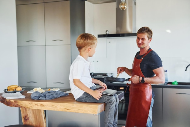 Préparer de la nourriture Père et fils sont à l'intérieur ensemble à la maison