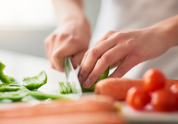 Préparer un repas sain rempli de bienfaits biologiques Gros plan d'une jeune femme coupant des légumes dans la cuisine