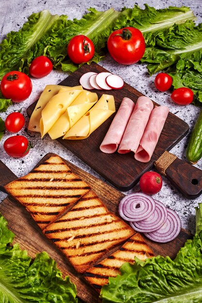 Préparer un sandwich au bacon maison fraîche sur une table en béton se bouchent, vue de dessus. Verticale.