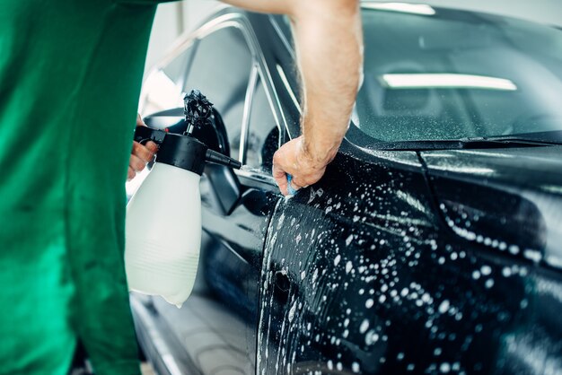 Préparer La Voiture, Protéger Contre Les éclats Et Les Rayures. Le Travailleur Disperse De L'eau Savonneuse.