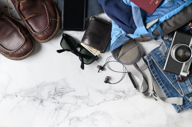 Préparez des accessoires de sac à dos et des articles de voyage sur fond de marbre avec un espace de copie plat