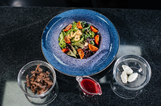 Préparez une délicieuse salade fraîche de feuilles de tomates, de fromage, de veau et de noix de cajou. Délicieuse nourriture saine.