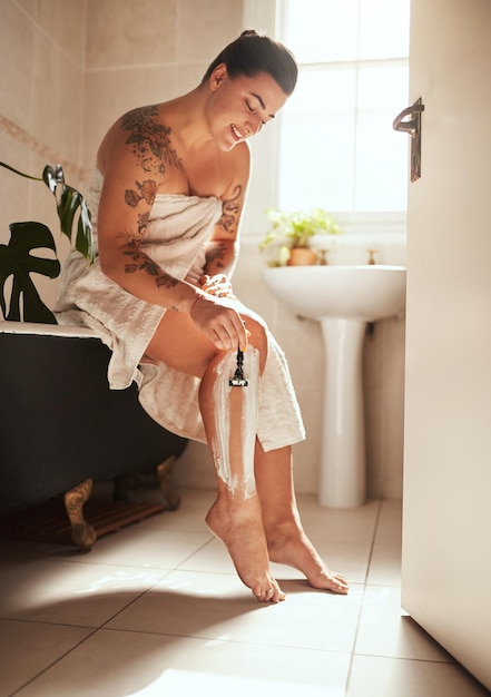 Préparez-vous à avoir de longues jambes Photo d'une jolie jeune femme se rasant les jambes dans la salle de bain à la maison