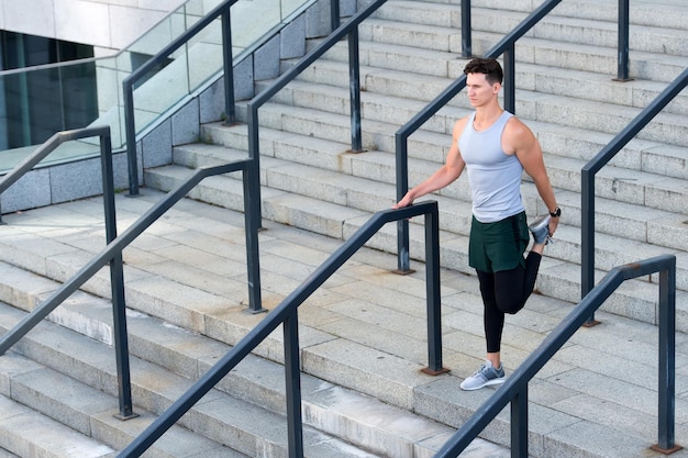 Préparez-vous pour le jogging, le gars s'échauffe avant l'entraînement en milieu urbain.