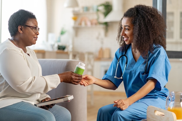 Préposé médical attentionné. Femme âgée reconnaissante prenant des pilules d'un assistant médical attentionné dans la maison de soins infirmiers