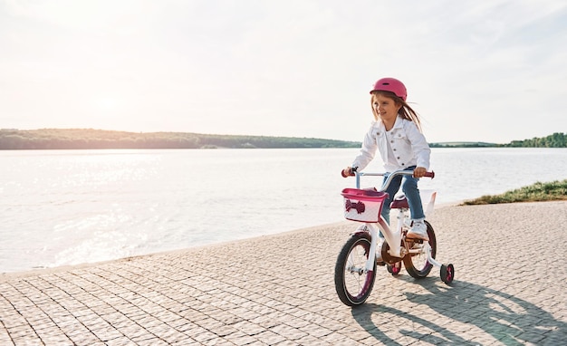 Près du lac Bonne petite fille faisant du vélo à l'extérieur en été