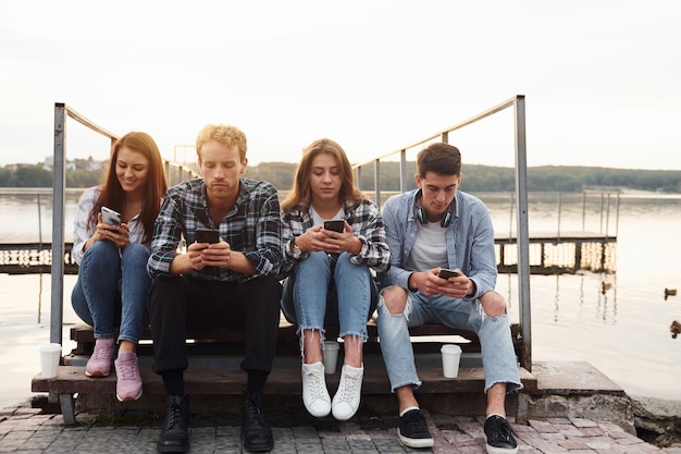 Près du lac Groupe de jeunes amis joyeux qui s'amusent ensemble à l'extérieur