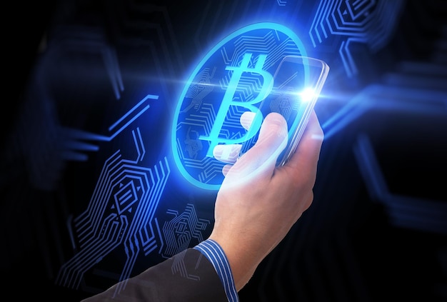 près de la main avec le smartphone et le bitcoin