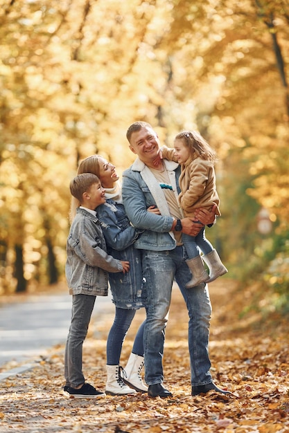 Près de la route Une famille heureuse est dans le parc à l'automne ensemble