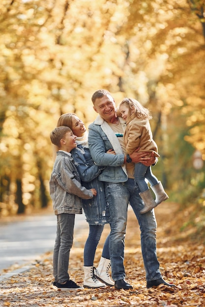 Près de la route Une famille heureuse est dans le parc à l'automne ensemble