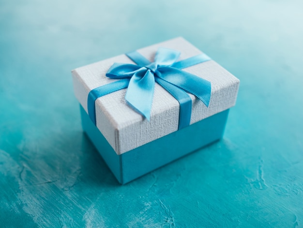 Présent dans une boîte cadeau sur fond bleu. Récompense de vacances ou d'anniversaire. Notion de célébration