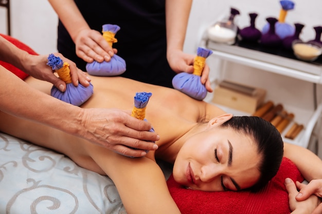 Présentation dos nu. Jeune femme calme avec les yeux fermés obtenant une séance méditative dans un salon de beauté professionnel