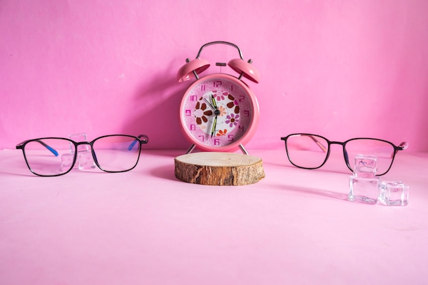 Présentation du produit de l'idée de concept minimaliste. verres, bûches, glaçons et réveil sur fond de papier rose.