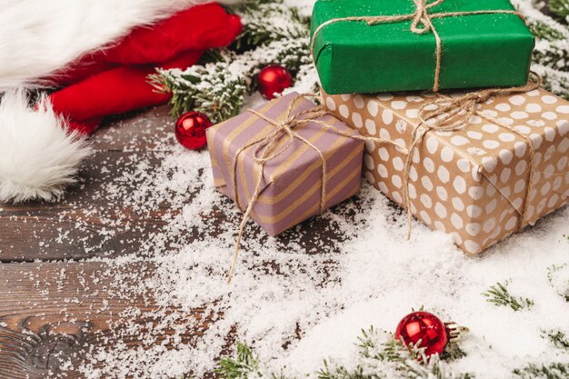 Présente sur un fond en bois avec des branches de sapin et des boules rouges poudrées de neige