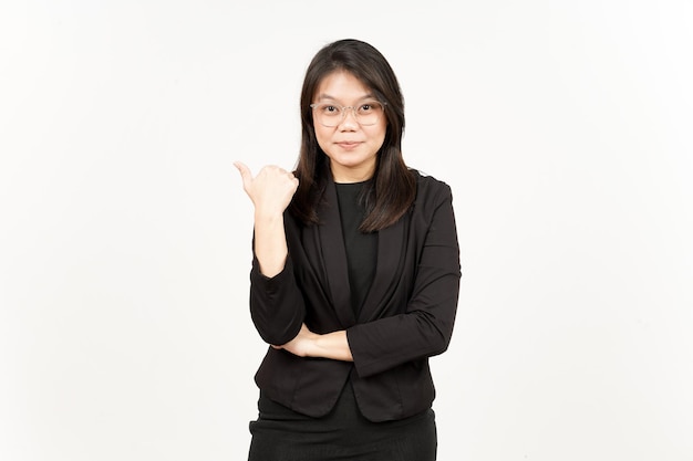 Présenter et pointer le produit latéral à l'aide du pouce d'une belle femme asiatique portant un blazer noir