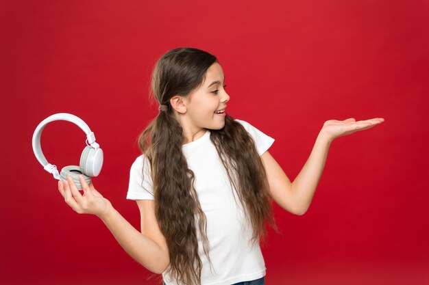 Présenter quelque chose. Petit enfant utilisant la technologie pour les loisirs ou l'éducation. Fan de musique mignon avec casque sans fil. Petite fille écoutant de la musique. Petite fille portant des écouteurs stéréo, copiez l'espace.