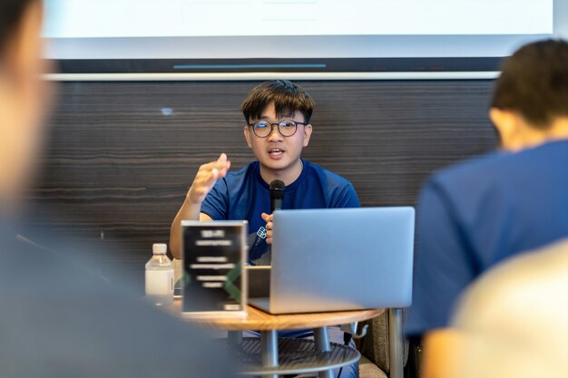 Président asiatique ou conférence avec costume décontracté donnant un discours devant la salle présentant