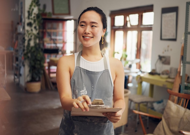 Presse-papiers de femme asiatique et propriétaire d'entreprise créative avec le sourire pour la conception d'art ou le démarrage dans l'atelier Heureuse femme japonaise souriante pour l'inspection de la gestion ou la liste de contrôle pour les arts et l'artisanat