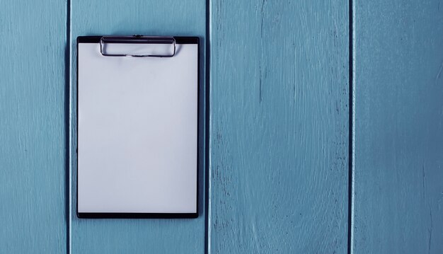 Presse-papiers avec une feuille blanche sur fond de bois.