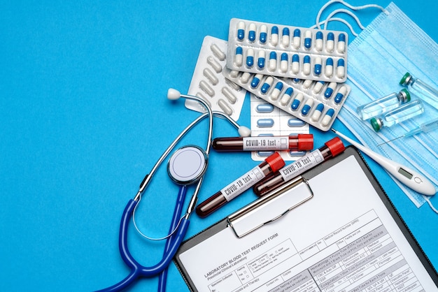 Presse-papiers avec formulaire vierge de papier avec des outils médicaux sur fond bleu avec espace pour faire face.