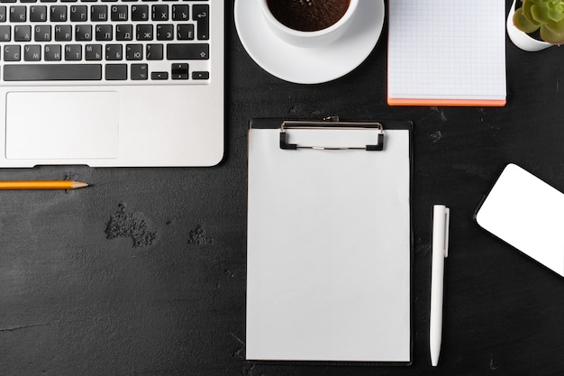 Presse-papiers maquette sur l'espace de travail du bureau à domicile avec tasse à café et papeterie