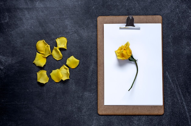 Photo presse-papiers avec et un pétale de rose jaune sur fond noir. la saint valentin