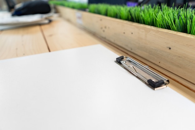 Un presse-papiers en plastique vide blanc était posé sur la table en bois.