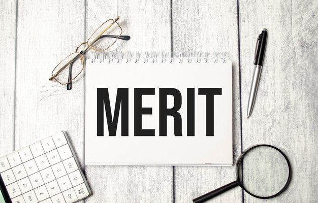 Presse-papiers avec texte MERIT et lunettes sur fond blanc