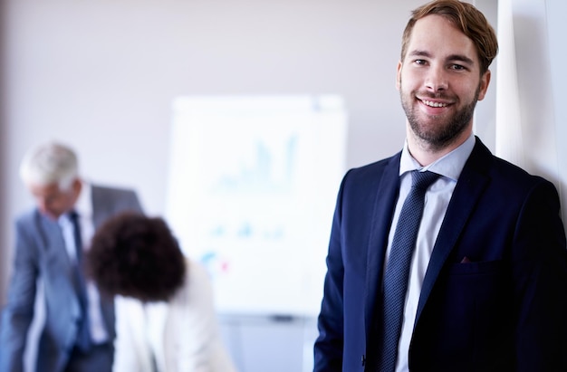 Prêt à faire sa marque Vue recadrée d'un jeune homme d'affaires souriant debout lors d'une réunion