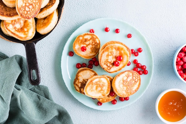 Photo prêt à manger des crêpes et des canneberges sur une assiette et un bol de miel sur la table