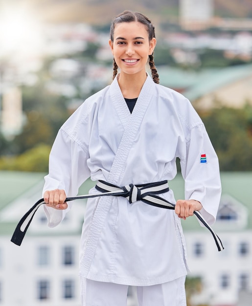Prêt pour le karaté et portrait d'une femme s'entraînant sur un toit pour une compétition d'événements professionnels et se battre Fitness ceinture noire et fille de taekwondo avec un sourire pour la puissance du corps sportif et les arts martiaux