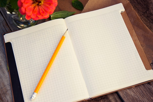 prêt pour le texte. Fleur rose et cahier ouvert sur la vieille table en bois. Vue de dessus. fond