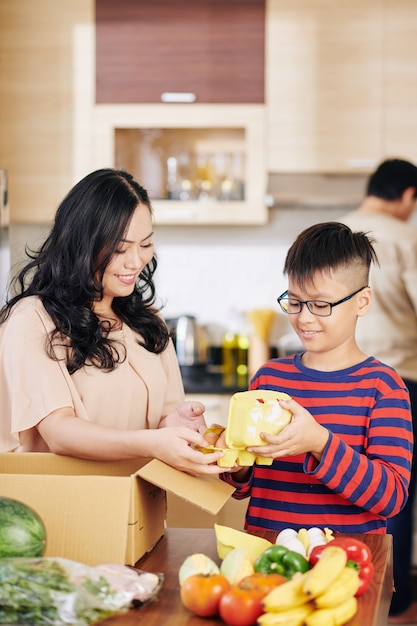 Preteen garçon vietnamien aidant sa mère à faire ses courses hors de la boîte en carton