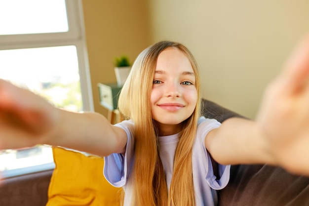 Preteen girl faisant des photos de selfie sur son smartphone dans un salon confortable à la maison