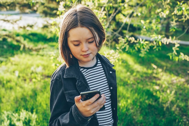 Preteen girl holding phone à l'aide de téléphone portable pour discuter avec des amis Concept de technologie moderne