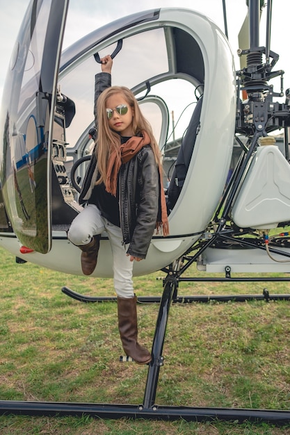 Photo preteen girl in miroir lunettes debout sur le marchepied d'un hélicoptère ouvert